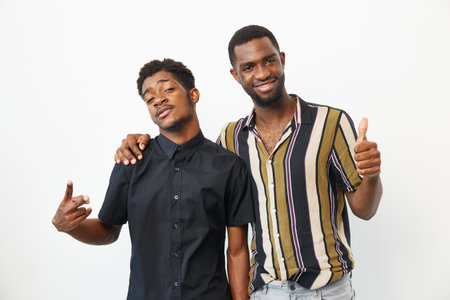 Two stylish African American men posing confidently, showcasing their fashion sense and vibrant personalities on a bright background, encapsulating modern friendship.の写真素材