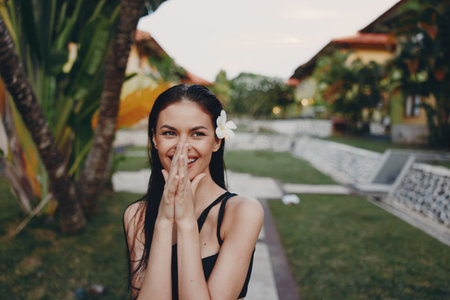 Young woman posing with hands on face and flower in hair for a beautiful and natural portrait shotの写真素材