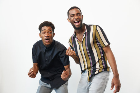 Cheerful African American men enjoying a joyful moment together, expressing excitement and happiness. Their vibrant clothing complements the lively atmosphere. ###の写真素材
