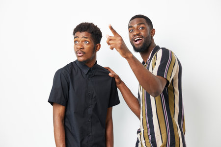 Two African American men interacting joyfully, one pointing while the other looks surprised, showcasing a moment of excitement. Perfect for celebratory themes.の写真素材