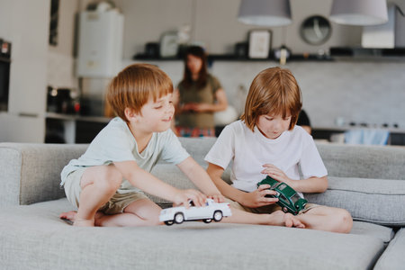 Two playful boys enjoying their toy cars in a cozy living room, surrounded by a warm atmosphere and minimalist decor, perfect for family moments.の写真素材