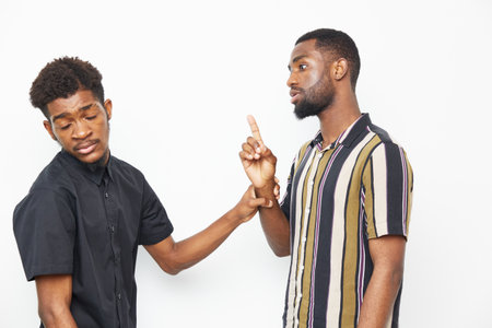Two African American men engaged in conversation, one gesturing thoughtfully while the other listens attentively, showcasing a moment of connection and understanding.の写真素材