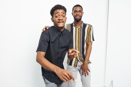 Black men smiling and having fun together, showcasing friendship and joy in a stylish urban...