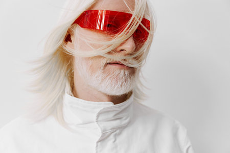 Futuristic portrait of a person with white hair and red sunglasses against a white background, exuding a modern, avant garde vibe with a bold fashion statementの写真素材