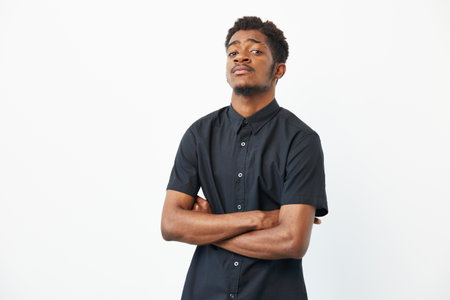 Confident black man posing with crossed arms, showcasing style and determination. His strong...