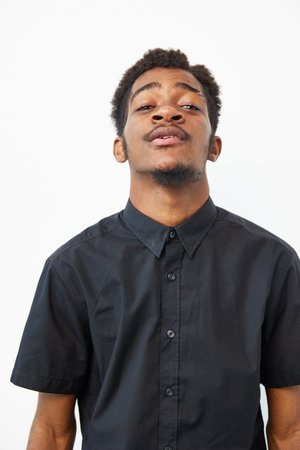 A confident black man in a black shirt exudes charisma and poise, showcasing his unique style. This...