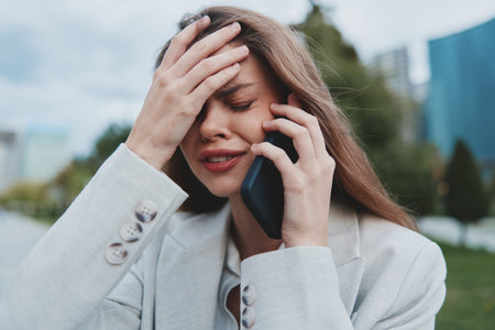 Stressed woman in business suit talking on smartphone outdoors showing anxiety and financial crisis...