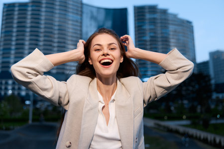 happy woman laughing outdoors in white jacket with modern buildings background city lifestyle business conceptの写真素材
