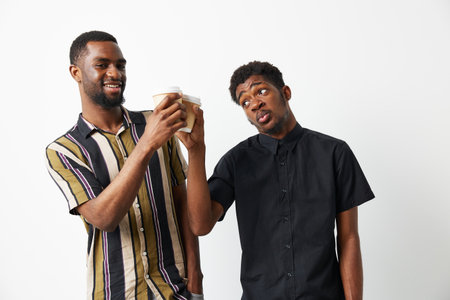 Two black men enjoying coffee together, sharing laughter and joy, showcasing friendship and camaraderie in a casual setting.の写真素材