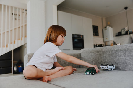 Young boy playing with toy cars indoors, showcasing creativity and joy in a cozy living room setting, emphasizing playtime and imagination.の写真素材