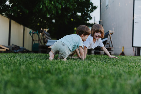 Happy children playing on the grass in the backyard. The joyful atmosphere captures their laughter and innocence.の写真素材