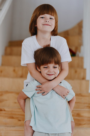 Two joyful boys playing together indoors, showcasing their playful spirits and brotherly bond in a charming home environment with natural light.の写真素材