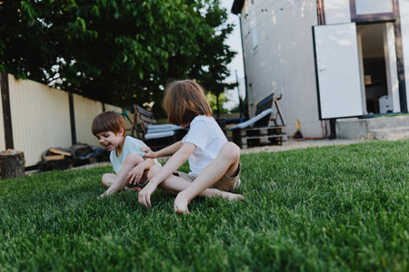 Playful children enjoying a sunny day, smiling and laughing in a grassy backyard, capturing moments of joy and innocence in nature.の写真素材