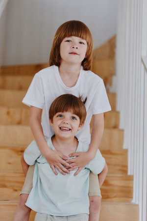 Two cheerful boys playfully pose on a staircase, radiating joy and energy. Their playful interaction captures the essence of childhood friendship and fun.の写真素材