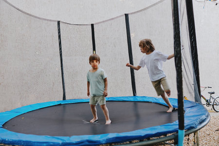 Two joyful boys bouncing on a trampoline, showcasing their playful nature and happiness. This engaging scene captures the essence of childhood fun and energy.の写真素材
