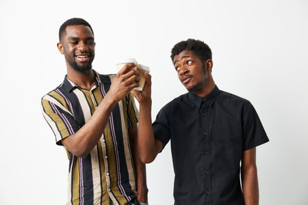 Two black men smiling and enjoying coffee together. Their joyful expressions and stylish outfits create a vibrant and engaging atmosphere.の写真素材