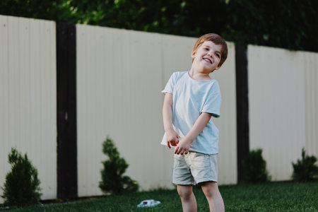 Joyful young boy playing outdoors in a sunny garden, showcasing happiness and carefree childhood spirit, capturing the essence of playful moments.の写真素材