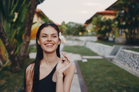 Happy woman posing in front of building with palm tree in background on sunny dayの写真素材