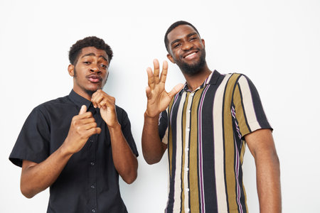 Two black men smiling and posing cheerfully against a light background, showcasing joy and...