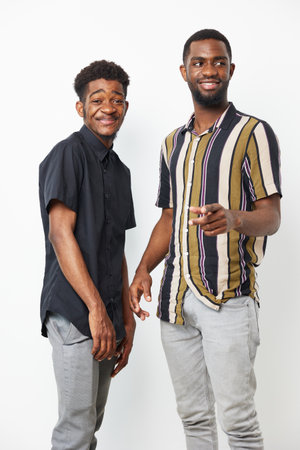 Two cheerful Black men posing together in stylish outfits, showcasing camaraderie and joy with a light-hearted atmosphere against a neutral backdrop.の写真素材