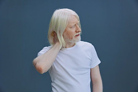 Portrait of a thoughtful elderly man with long white hair against a soft blue background, feeling...