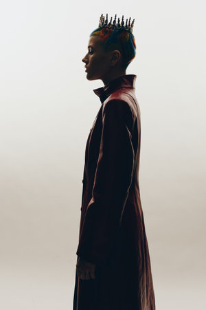 Creative woman with unique crown hairstyle and red leather coat in profile against white background,...