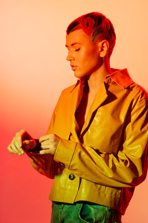 Young woman with red hair wearing a yellow jacket poses thoughtfully against an orange-red...