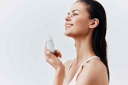 skincare, beauty, wellness, woman, smiling, minimalistic, product, indoor, natural, fresh, grooming, personal care, cosmetics, promotional image of a woman holding a skincare product with a bright smile against a neutral backgroundの写真素材