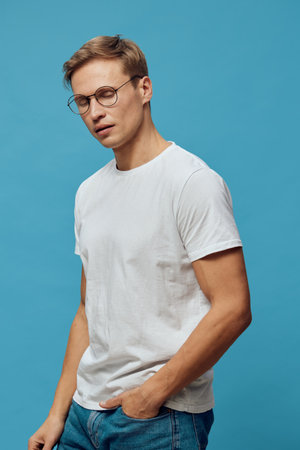 thoughtful young man wearing glasses white t-shirt blue jeans studio portrait digital detox mental...