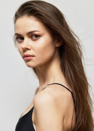 Elegant woman with long hair looking over her shoulder, showcasing natural beauty and confidence. Light background enhances her features and expression.の写真素材