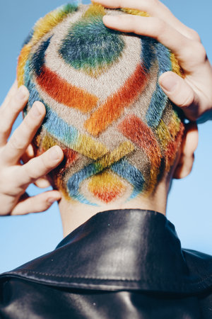 Creative woman with colorful dyed buzz cut viewed from behind, vibrant hair patterns and black...