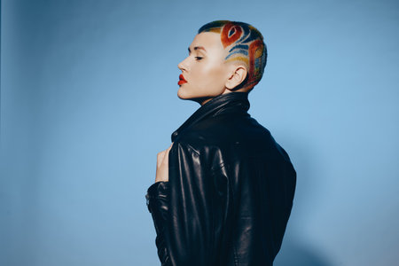 Woman with colorful shaved hairstyle and red lipstick wearing black leather jacket on blue...