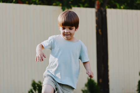 Happy boy playing outdoors, enjoying the sunshine and a carefree moment, showcasing the joy of childhood and playful spirit in a vibrant green setting.の写真素材