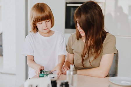 Caring woman and child enjoying quality time together while exploring technology, showcasing the bond between parent and child in a modern home setting.の写真素材