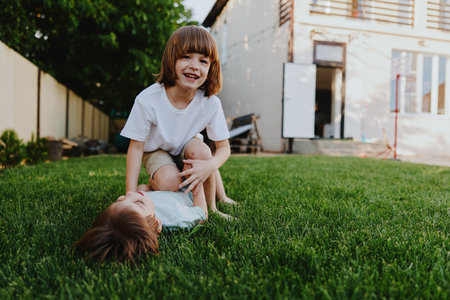 Joyful children playing together in the garden, enjoying a sunny day, laughter, and friendship fill...