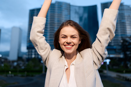Happy businesswoman celebrating success outdoors in a modern urban setting, showcasing confidence and positivity.の写真素材