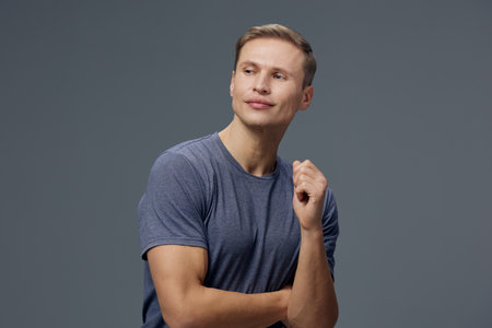 thoughtful man in blue t-shirt looking away on gray background portrait casual tech concept mental...