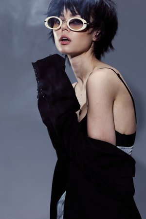 Stylish woman wearing sunglasses and black coat with short hair in artistic fashion portrait