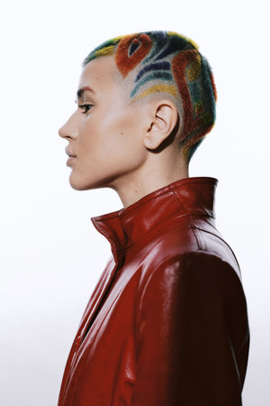 Woman with colorful short hair wearing a red leather jacket, showcasing bold style and creative...