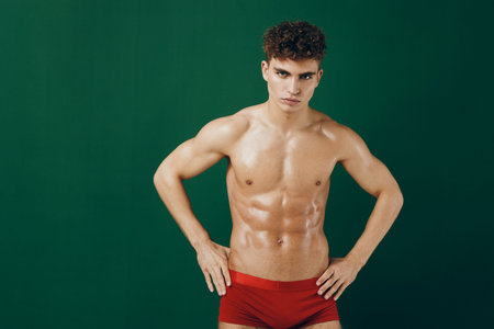 Confident muscular male model posing against a vibrant green background, showcasing fitness and strength. Body positivity and health concept.の写真素材