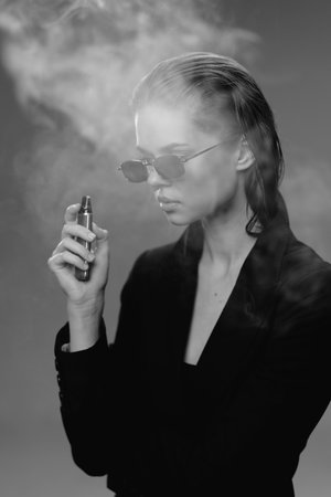 Stylish woman vaping in black and white with sunglasses and smoke around her in dark outfit