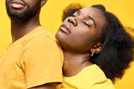 African couple in matching yellow outfits, expressing love and connection against a bright yellow...
