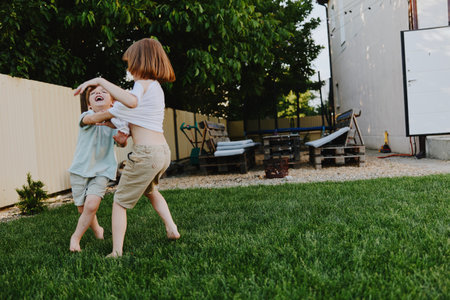 Two joyful children playing together in a green backyard, full of laughter and energy, capturing the essence of childhood fun and outdoor activities. ### Ð¡Ð¾Ð·Ð´Ð°Ð½Ð¸Ðµ ÐÑÐ¾ÑÐ¾Ð³Ð¾ ÐÐ¿Ð¸ÑÐ°Ð½Ð¸Ñ (DESCRIPTION2):の写真素材