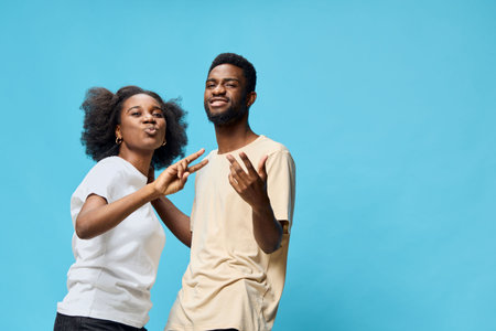 Joyful young couple having fun together against a blue background, showcasing happiness and...