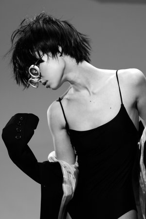 Black and white portrait of a woman with short hair wearing a black dress in an artistic pose.