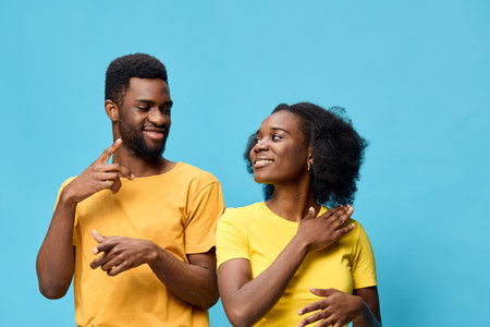 Cheerful couple in matching yellow t shirts against a bright blue background, expressing joy and connection, perfect for lifestyle and relationship themesの写真素材