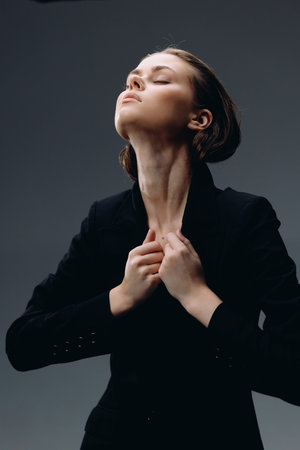 confident woman in black suit with closed eyes expressing empowerment and elegance in studio settingの写真素材