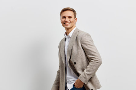 Smiling man dressed in smart casual outfit, beige blazer and white shirt, professionally posing with...