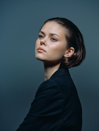 Portrait of a young woman with short hair wearing dark clothing, looking away with a contemplative expression.の写真素材