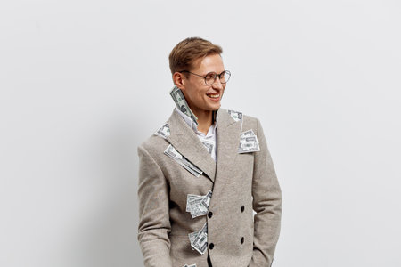 Smiling person with short brown hair and glasses wearing a stylish plaid coat standing against a plain light gray background. Casual fashion and joyful expression. Concept: positive mood and modern style.の写真素材